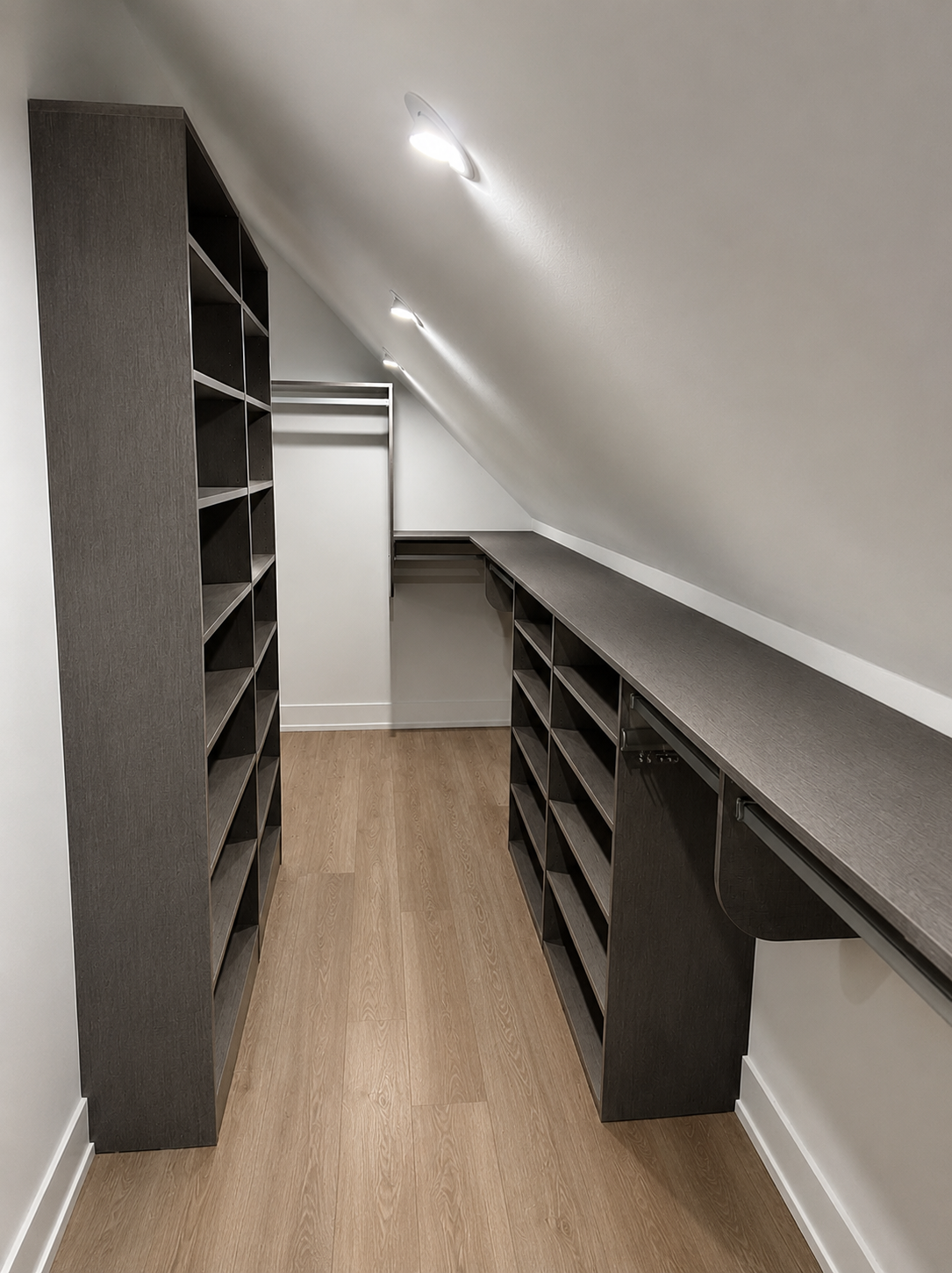 Custom dark oak attic closet with angled ceiling shelving and full-length counter