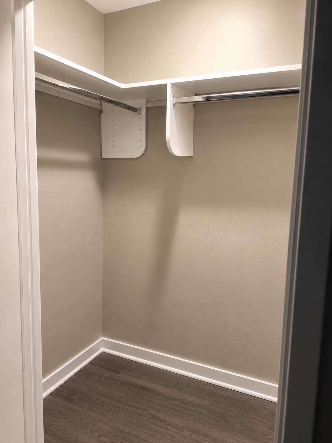 Minimal walk-in closet with LED-lit top shelf and chrome hanging rods